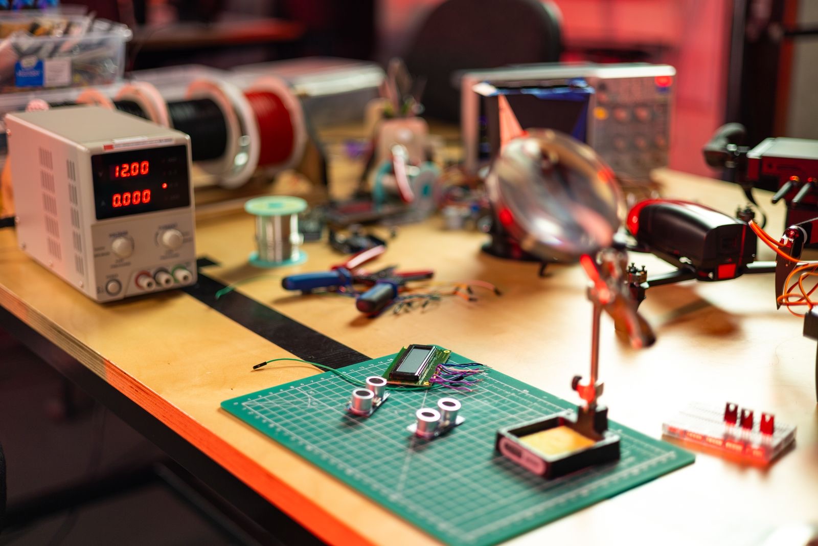Electronics workbench with a bench power supply, oscilloscope and a sensor module wired on a cutting mat